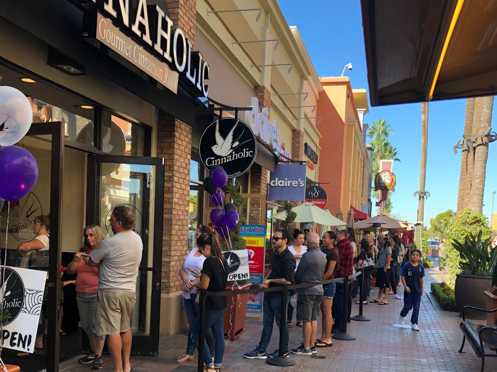 Long line of people waiting to get inside a Cinnaholic store